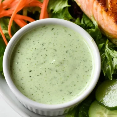 Creamy basil dressing in a bowl with fresh basil leaves.