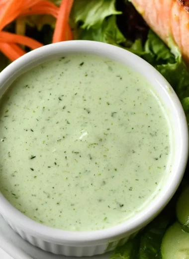 Creamy basil dressing in a bowl with fresh basil leaves.