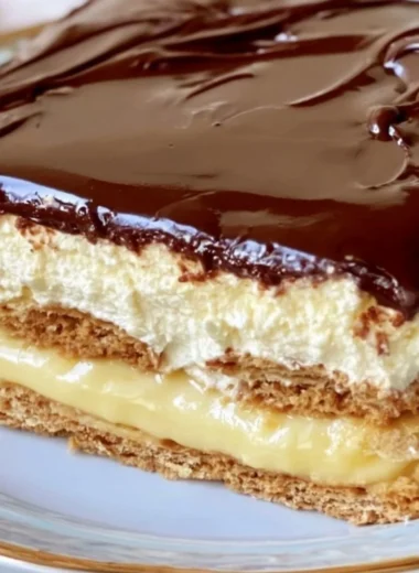Delicious no-bake eclair cake topped with chocolate icing and whipped cream