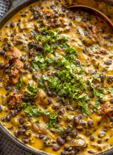 Cozy creamy black bean curry served in a bowl with fresh herbs and spices