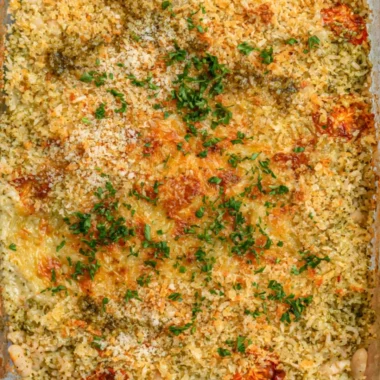 Cozy white bean pesto bake topped with fresh basil and cheese