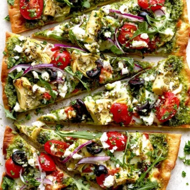 A delicious Mediterranean flatbread pizza topped with fresh vegetables and herbs.