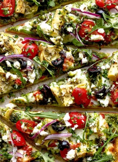 A delicious Mediterranean flatbread pizza topped with fresh vegetables and herbs.