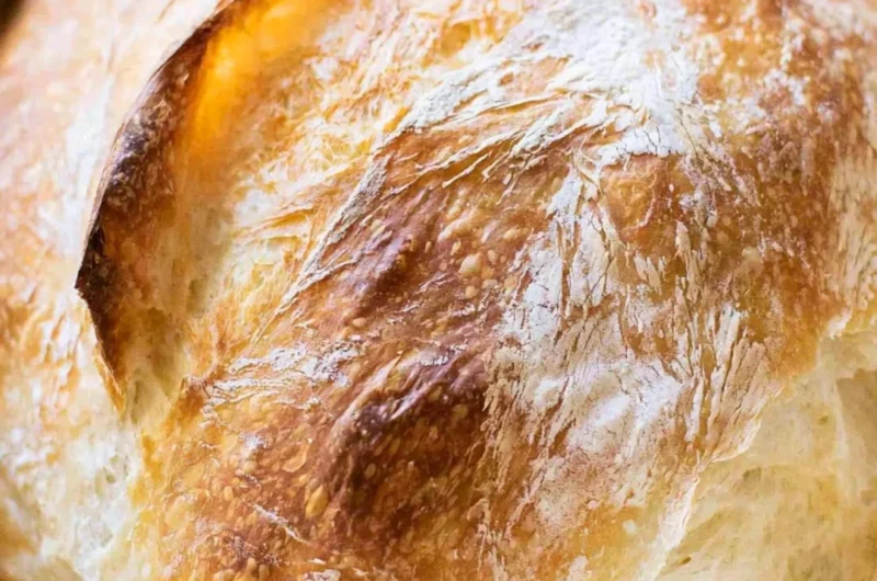 A freshly baked loaf of no-fail sourdough bread on a wooden table