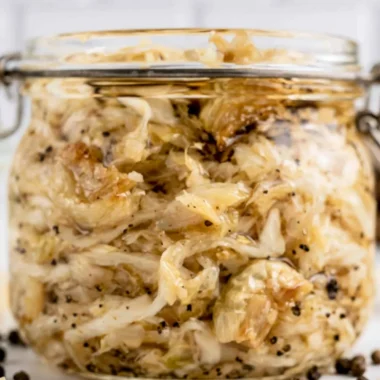 Jar of homemade roasted garlic sauerkraut with cloves of garlic