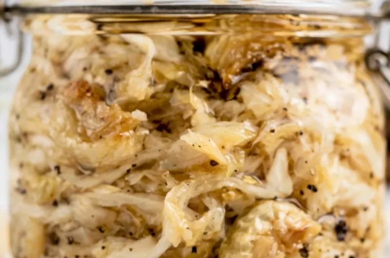 Jar of homemade roasted garlic sauerkraut with cloves of garlic