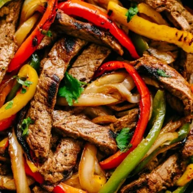 Skillet steak fajitas with colorful bell peppers and onions in a cast-iron skillet