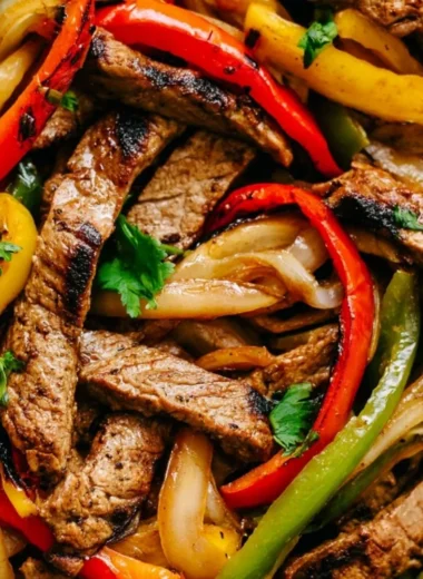 Skillet steak fajitas with colorful bell peppers and onions in a cast-iron skillet