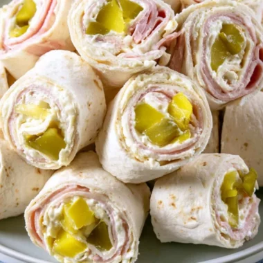 Cozy Pickle Dip Pinwheels served on a wooden platter with fresh herbs.