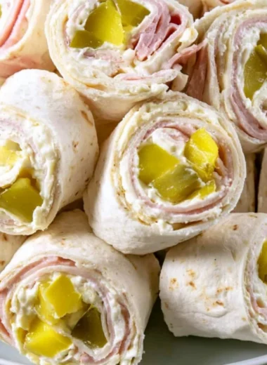 Cozy Pickle Dip Pinwheels served on a wooden platter with fresh herbs.